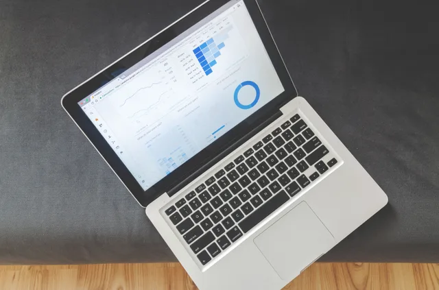 Overhead view of a laptop showing data visualizations and charts on its screen. Affiliate and platform fee models for influencer agencies