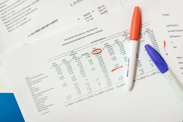 Close-up of financial documents with highlighted figures and marker pens. When an agency screens for fraud on a client's behalf, who decides and who is told