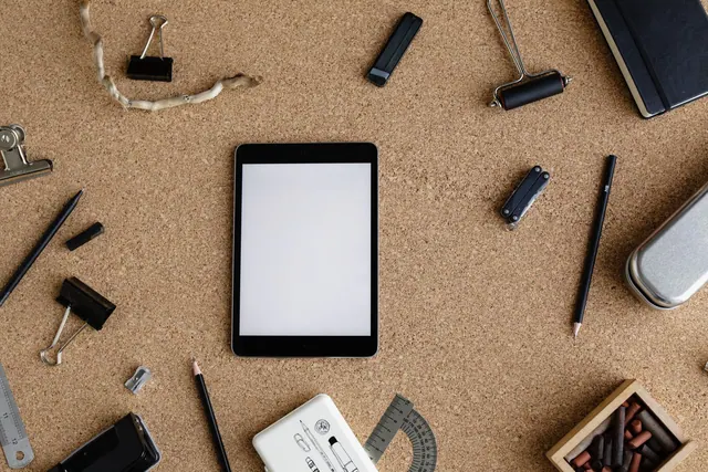 Flat lay of a cork board workspace with various stationery items and a tablet for creative office tasks. Campaign management tools case studies: evidence and results