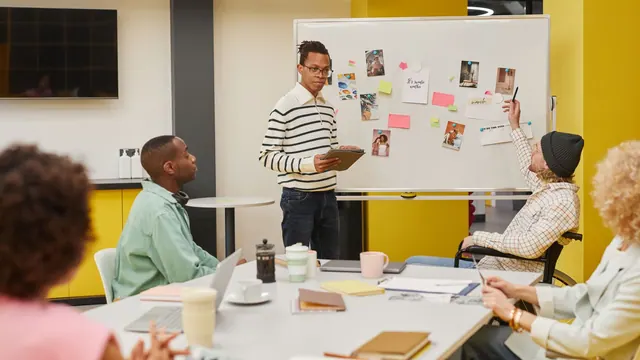 A diverse team engaged in a collaborative meeting around a whiteboard in a modern office setting. Discovery platforms strategy explained for 2027