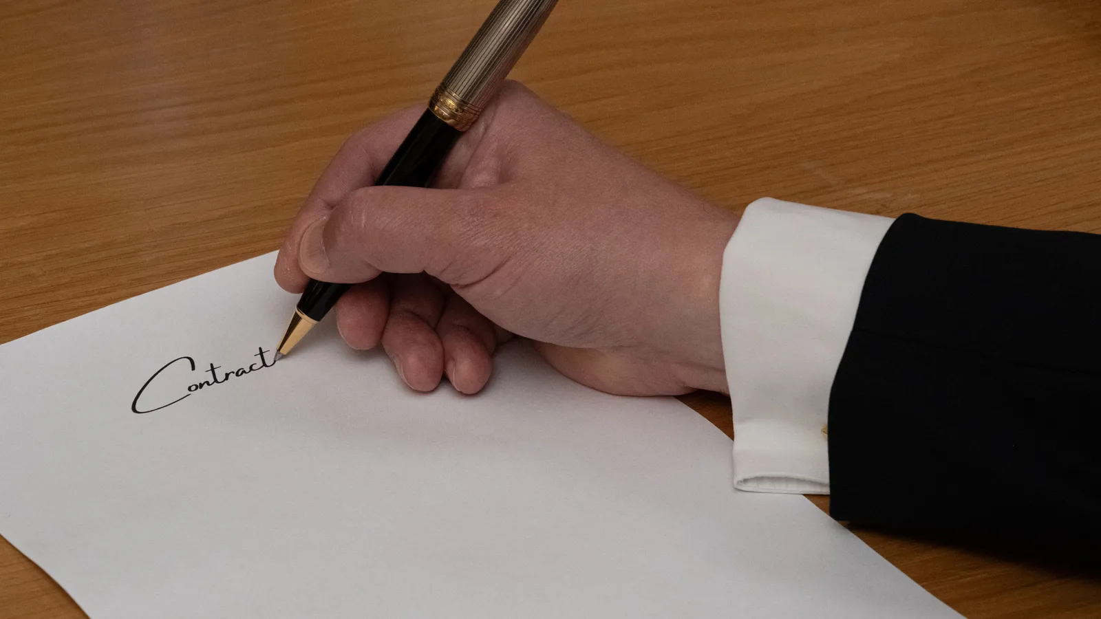 A professional signing a business contract with a fountain pen on a wooden desk. Influencer Agency Red Flags: A US Buyer Checklist