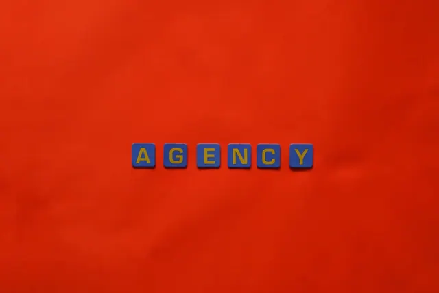 Blue letter tiles spelling 'AGENCY' on a vibrant red background, ideal for creative promotion. Talent agencies mistakes: practical details and examples